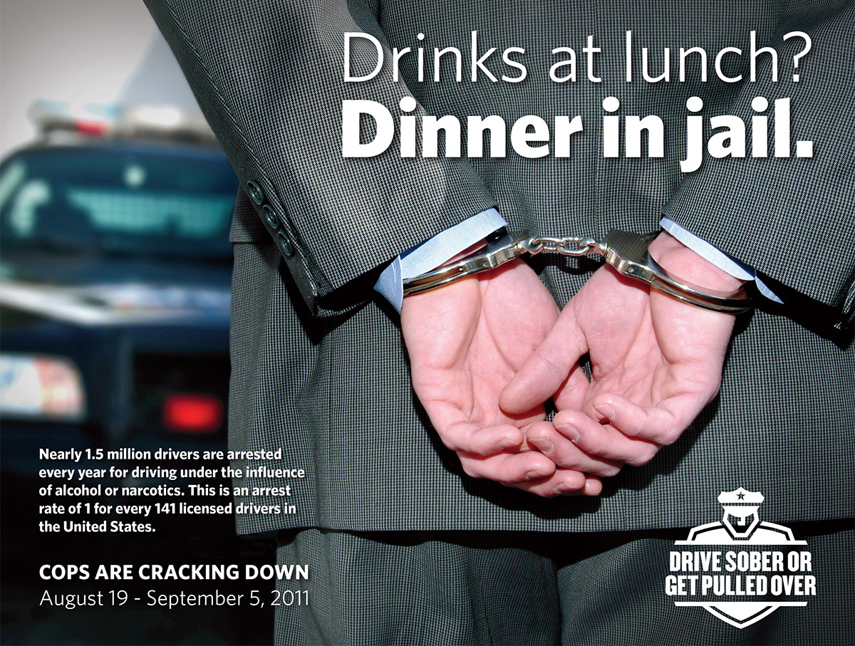 Hands cuffed behind the back of someone wearing a gray suit in a creative deliverable for the “Drive Sober or Get Pulled Over” campaign; an out-of-focus police car in the background.