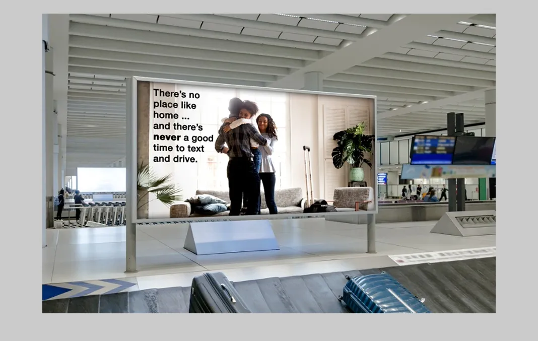 An airport transit ad featuring a family in their home with the text 'There's no place like home…and there's never a good time to text and drive.' published for the National Highway Traffic Safety Adminstration.