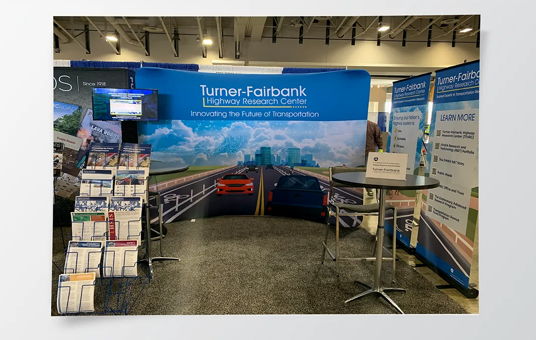 A trade show booth display with printed materials and a large retractable banner for the Innovating the Future of Transportation campaign published by the Turner-Fairbank Highway Research Center.